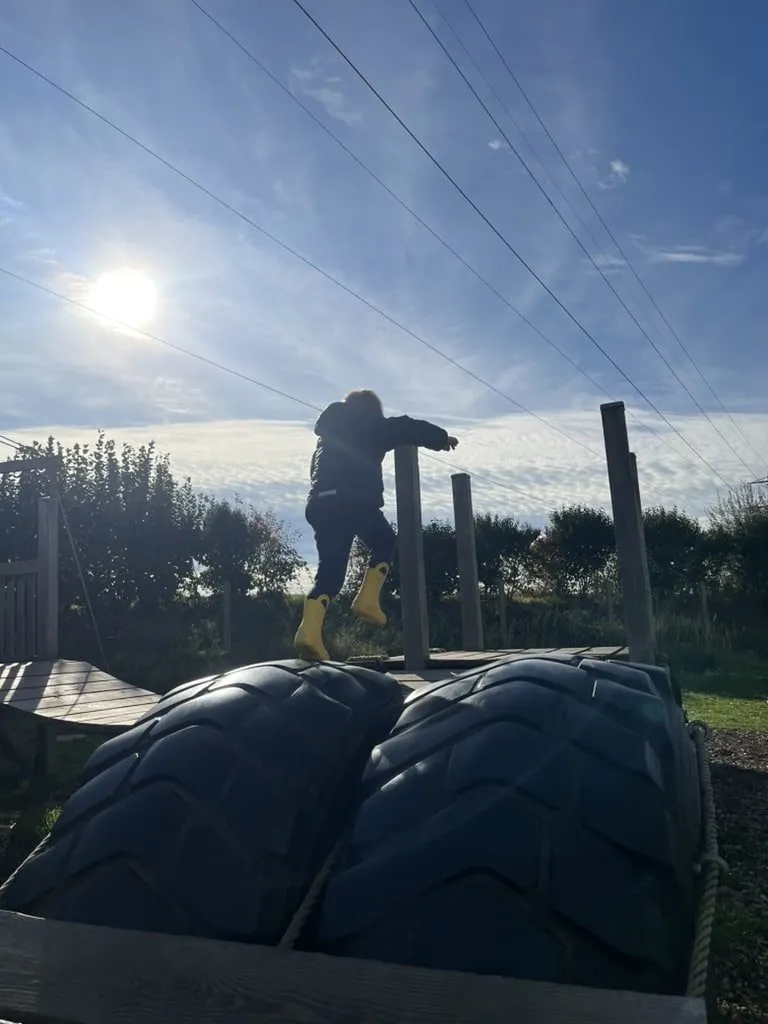 Kind klettert auf großen Traktorreifen