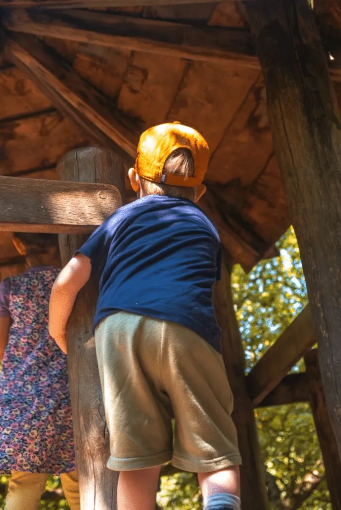 Kind klettert in einem hölzernen Spielturm