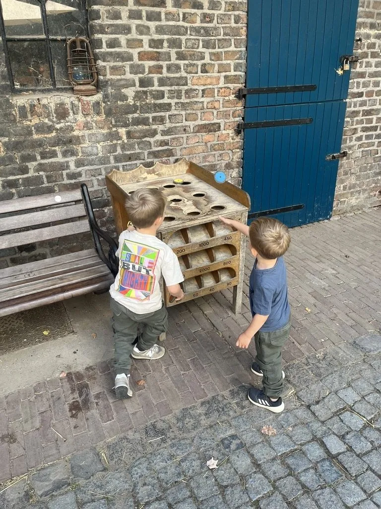 Zwei Jungen an einem hölzernen Spielgerät vor einer Backsteinwand