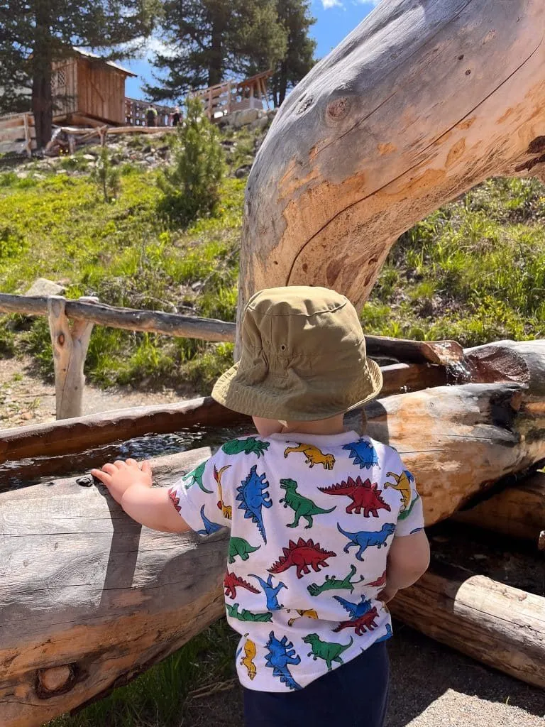 Kind mit Sonnenhut an einem Holzspielgerät