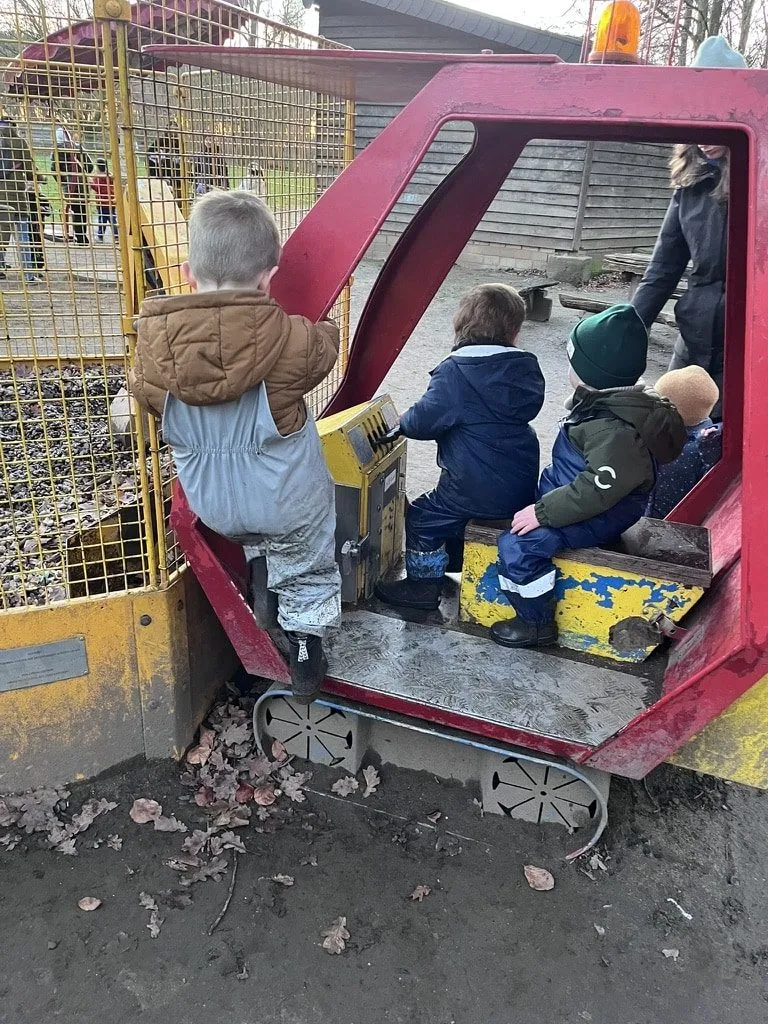 Kinder sitzen im Spielbagger auf dem Spielplatz